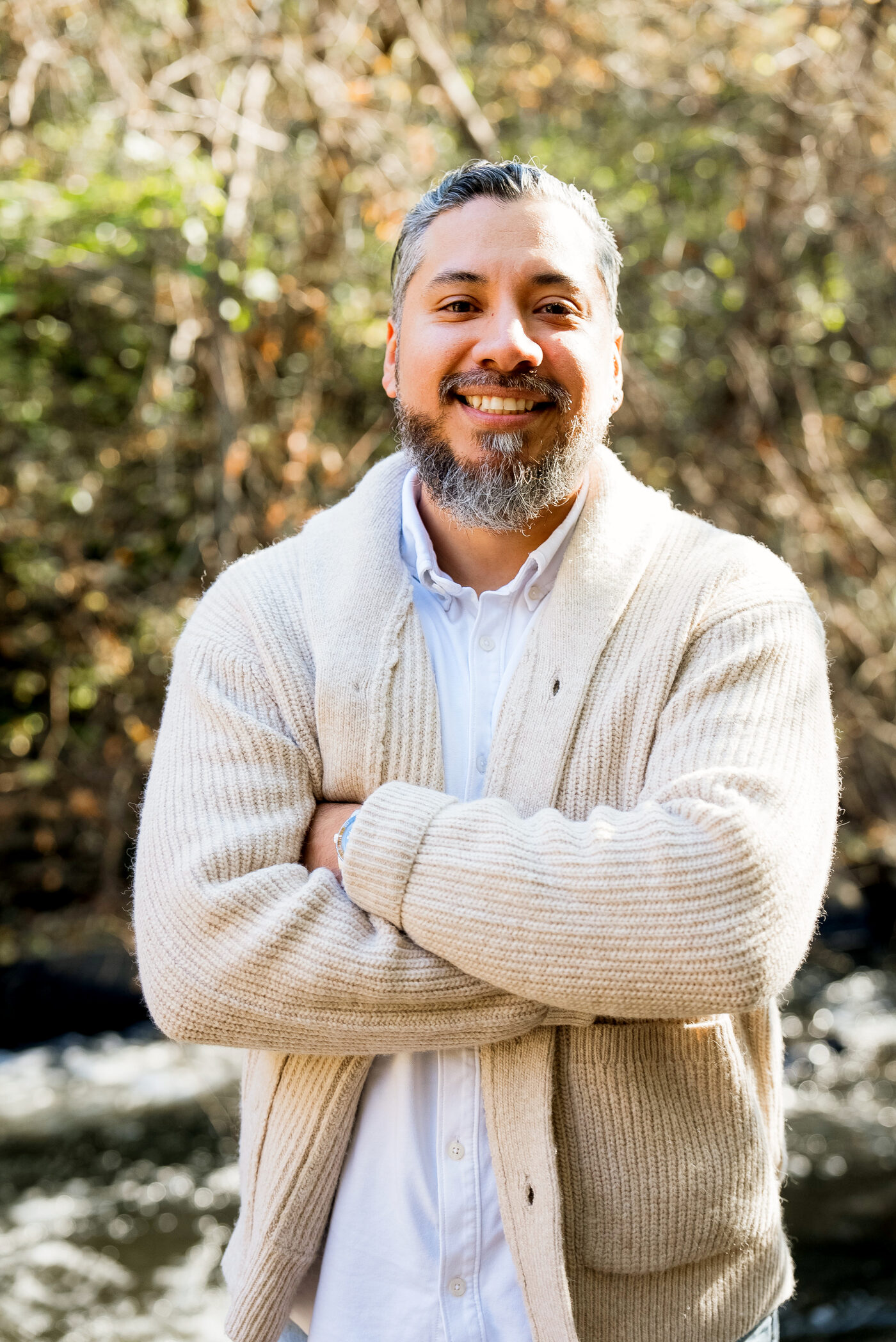 Alex of Martinez Engineering Group, smiling with arms crossed, in a cardigan outdoors